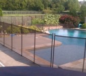 A pool with a fence around it and water in the background.