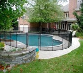 A pool with a fence around it and a tree in the background.