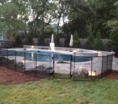 A pool with a fence around it and trees in the background.