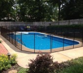 A pool with a fence around it and bushes in the background.