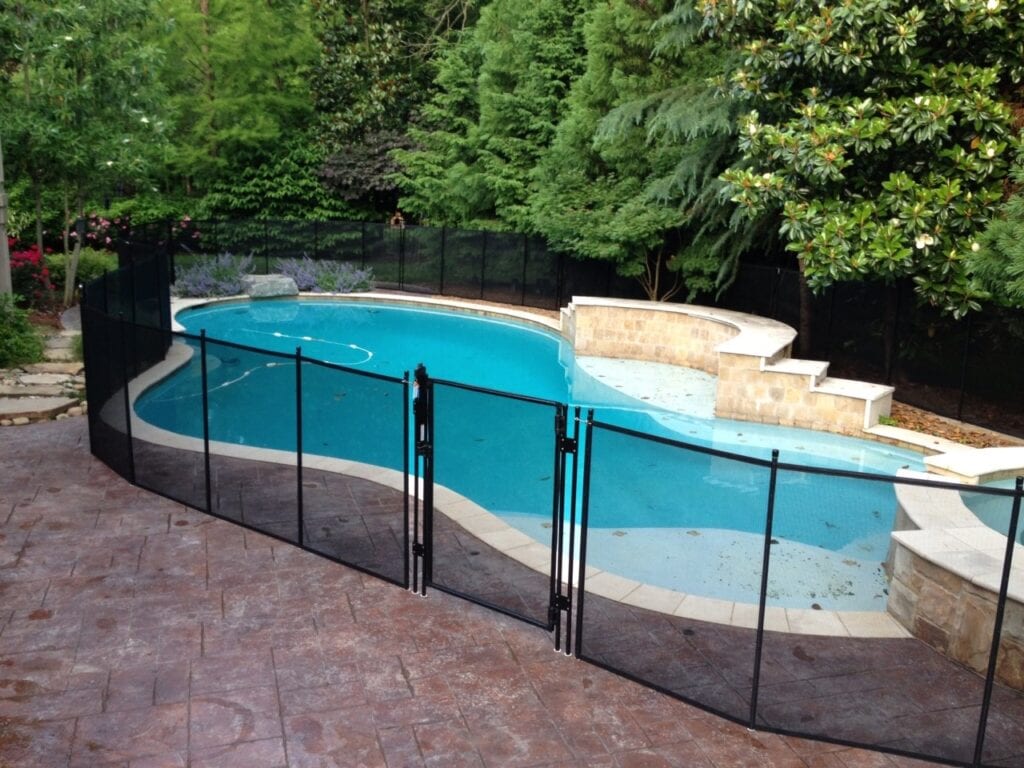 A pool with a fence around it and trees in the background.