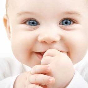 A baby with blue eyes is holding its hand to the mouth.